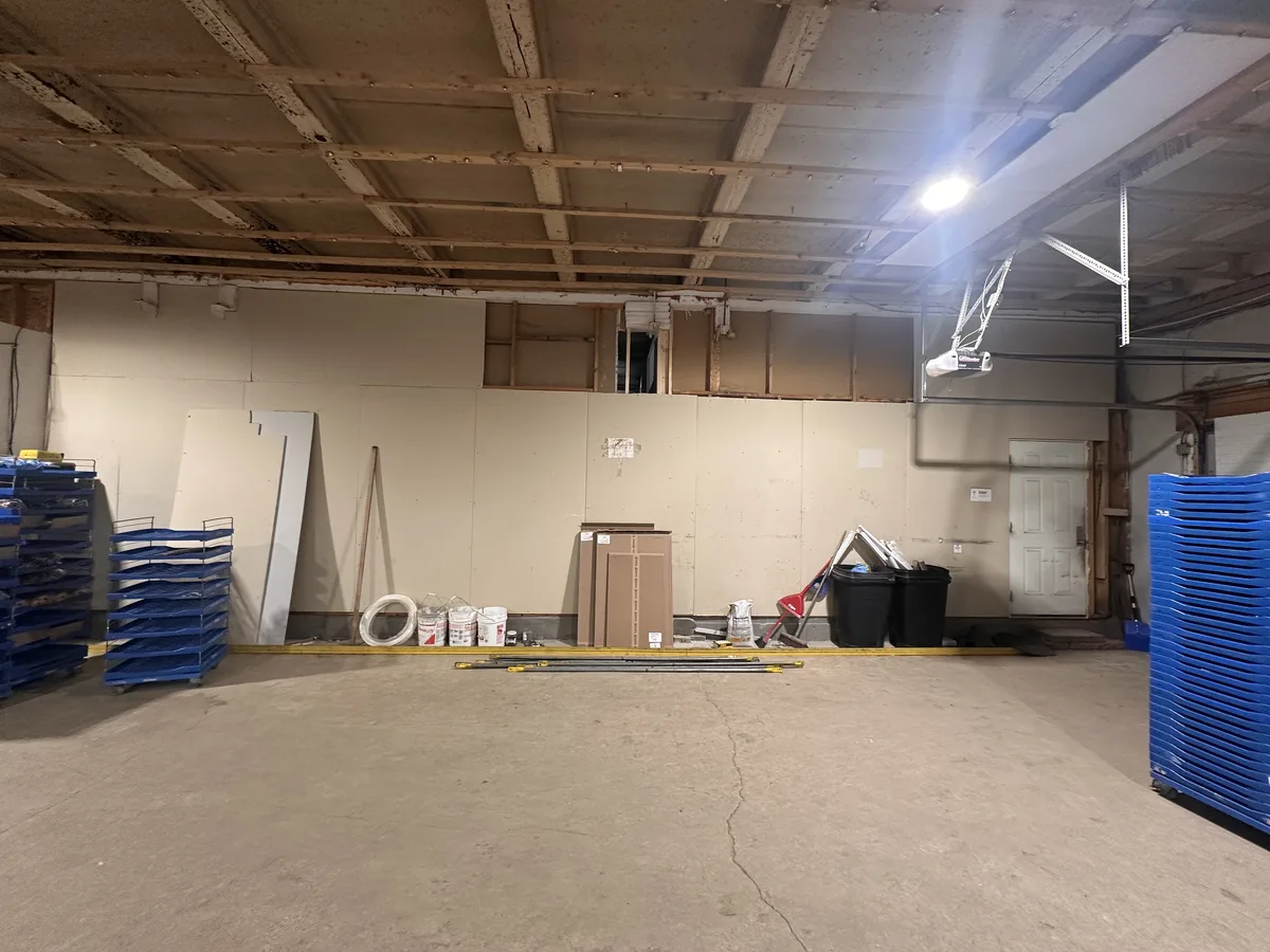 Unfinished warehouse wall with loose drywall sheets left mid-project